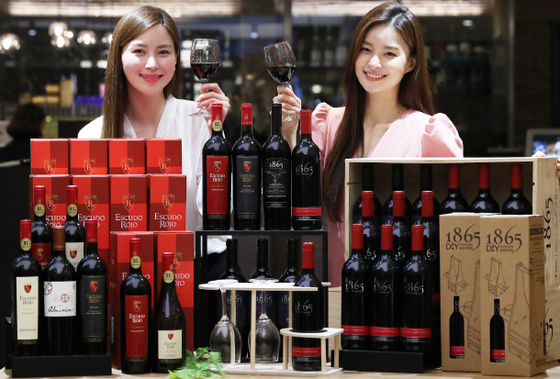 Models pose with wine at Lotte Department Store’s branch in central Seoul on Tuesday. The retailer said throughout May it is holding a sale on Chilean wines 1865 and Escudo Rojo. [YONHAP]