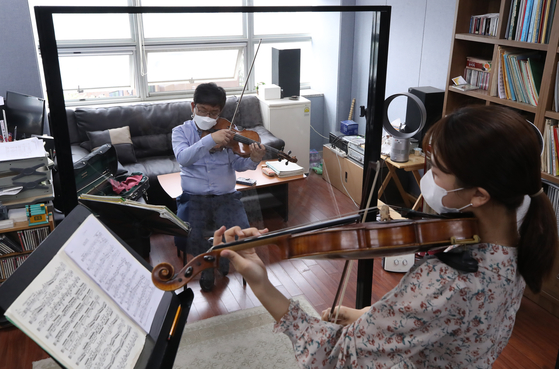 A music professor at Seoul National University instructs his student in viola while separated by a transparent divider set up to abide by social distancing guidelines. [YONHAP]