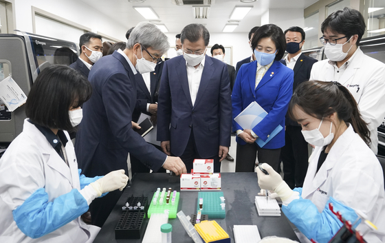President Moon Jae-in, center, examines a Seegene research facility during his visit to the company’s headquarters in Seoul in March. Moon visited the local diagnostic kit manufacturing company following his phone conversation with U.S. President Donald Trump hours earlier. [YONHAP]