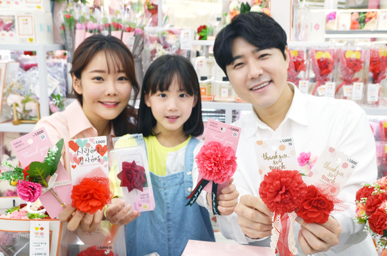 Models show carnation brooches at the Family Month Exhibition section at Daiso's Coex branch in Gangnam District, southern Seoul on Thursday for the upcoming Parents' Day. [ASUNG DAISO]