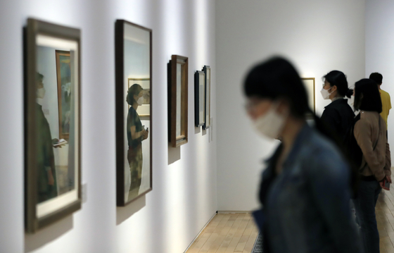 Visitors look at works on display at MMCA Seoul’s permanent exhibition ’MMCA Collection Highlights 2020+“ on Thursday in central Seoul while wearing masks and standing away from each other in an effort to abide by social distancing guidelines. [YONHAP] 