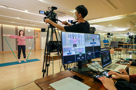 Pilates instructor Kim Eun-ah, left, teaches a resistance band workout in front of cameras at the cultural center of Hyundai Department Store’s Trade Center Store in Gangnam District, southern Seoul. Hyundai Department Store announced Wednesday that it will broadcast live from its cultural centers on its official YouTube channel. [HYUNDAI DEPARTMENT STORE]