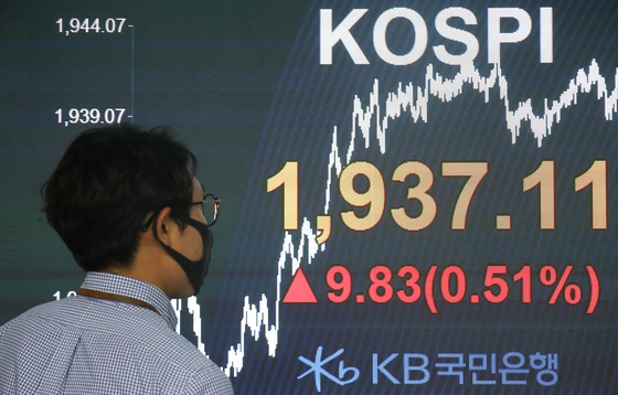 A dealer walks past an electronic signboard in the dealing room of KB Kookmin Bank in Yeouido, western Seoul, Monday. The Kospi closed at 1,937.11, a 9.83 point rise from the previous close. [YONHAP]