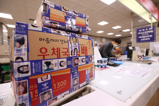 A delivery box is wrapped with Hope Tape at Gwanghwamun Post Office in central Seoul on Monday to mark International Missing Children’s Day. Hope Tape, available for customers to use as packaging tape at 22 general post offices in Seoul, is covered with descriptions of missing children. [YONHAP]