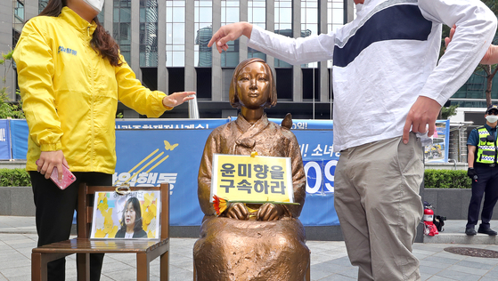 A statue symbolizing victims of Japanese wartime sexual slavery in Jongno District, central Seoul, on Monday is seen with a sign calling for the imprisonment of lawmaker-elect Yoon Mee-hyang, who has been questioned over her financial transparency by Lee Yong-soo, a "comfort woman" survivor. Two youth groups clashed over the placement of the sign that day. [YONHAP]