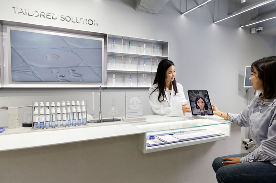 A customer at Iope Lab in Myeong-dong, central Seoul, sits for a photo to have her facial structure measured for a 3-D printed sheet mask. [AMOREPACIFIC]