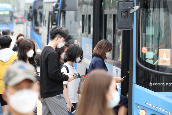 People are seen wearing face masks as they board a bus in Seocho District, southern Seoul, Monday, a day before a new rule goes into effect that allows bus and taxi drivers to refuse passengers without a face covering. [YONHAP]