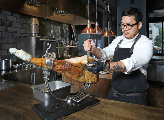 Chef Shin Seung-hwan of El Txoko de Terreno in Yongsan District, central Seoul, cuts slices of jamon at his restaurant. [PARK SANG-MOON]