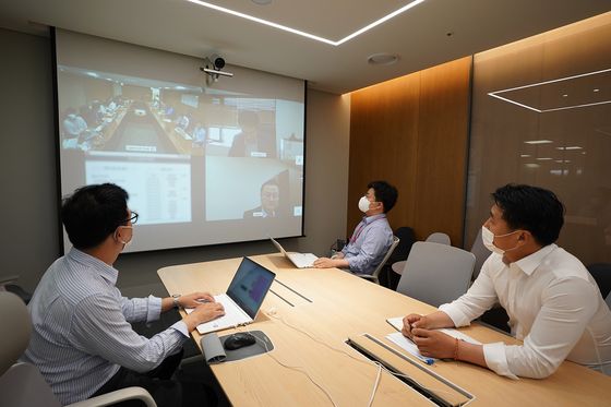 Lotte Duty Free workers hold a videoconference. The company started a telecommuting program for headquarters employees on Monday. [LOTTE DUTY FREE]  