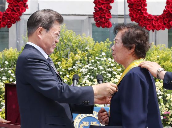 President Moon Jae-in, left, awards a Moran Medal to Bae Eun-shim, mother of the late student activist Lee Han-yeol, during the June 10 Democratic Protest anniversary ceremony on Wednesday.  [YONHAP] 
