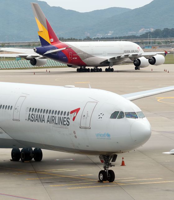 Asiana Airlines planes parked at the Incheon International Airport on Wednesday. The airline on Thursday rejected Hyundai Development Company’s Tuesday statement blaming the airline for not providing sufficient information. [YONHAP]