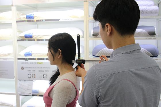 A consultant helps a customer find the right pillow for quality sleep. [EVEZARY]