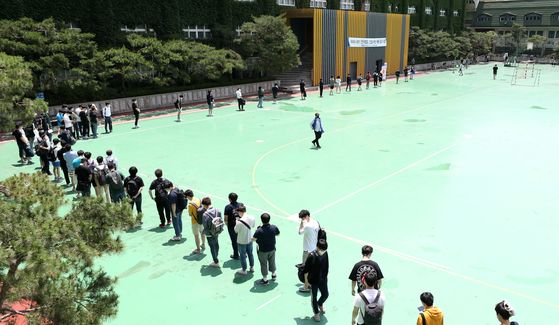 Applicants for jobs at Korea Railroad (Korail) queue up to enter a building on a college campus in Seongbuk District, central Seoul, Sunday afternoon, while practicing social distancing. Some 43,000 people applied to take the written exam, which was held in 24 test sites across the nation. [NEWS1]