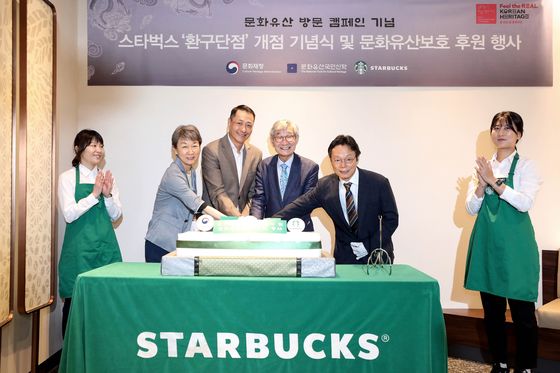 From left: Chung Jae-suk, administrator of the Cultural Heritage Administration and Song Ho-seob, CEO of Starbucks Korea, pose with other officials at the reopening event for Starbucks’ Hwangudan store in Jung District, central Seoul. [YONHAP]