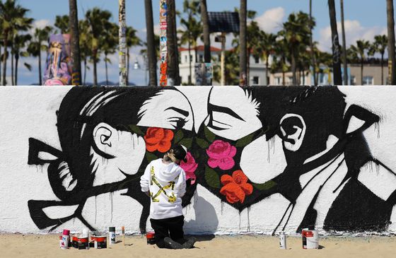 Artist Pony Wave paints a scene depicting two people kissing while wearing face masks on Venice Beach on March 21 in Venice, California. [AFP/YONHAP]