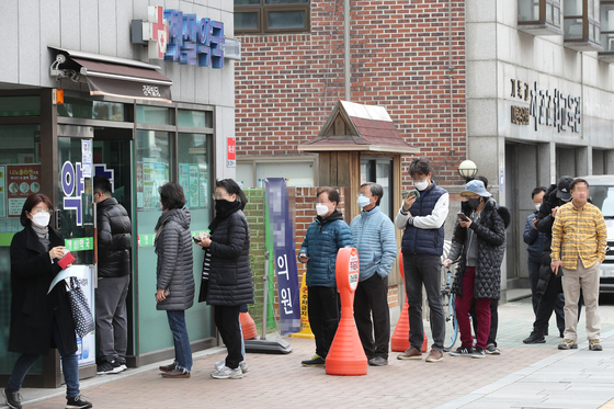 People line up in front of a drug store in Jongno District, central Seoul, to receive publicly-distributed masks on March 21. The national health insurance database was used in limiting the masks to two per person every week as there was a surge in demand after the number of coronavirus cases shot up after many Shincheonji members especially in Daegu contracted the virus, forcing the city to lock down. [YONHAP]
