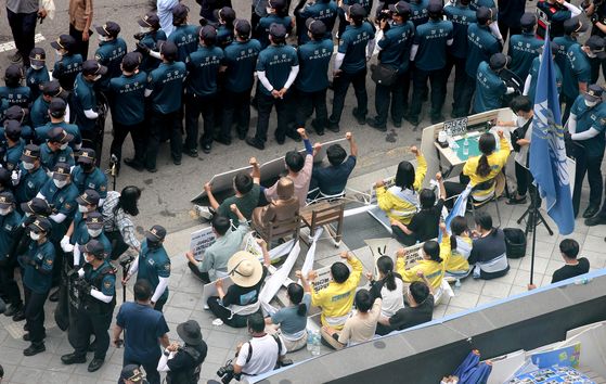 A group of college students stage a sit-in protest, tying their bodies with the Statue of Peace, to protect the symbol of victims of sexual slavery by the imperial Japanese military during World War II, near the Japanese Embassy in Seoul on Tuesday. Another group also staged a rally demanding the removal of the statue.  [YONHAP]