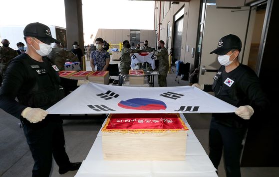 South Korean soldiers hold the country's national flag over a box containing the remains of fallen soldiers from the Korean War returned to the South on Wednesday. [NEWS1]