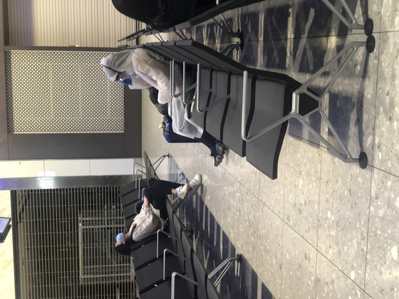 Passengers in hazmat suits wait for a flight in London’s Heathrow Airport on March 28. [YU JINSIL, JIM BULLEY]