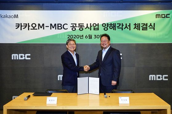 CEO of Kakao M, Kim Sung-soo, left, and MBC CEO Park Sung-jae pose for a photo after signing a memorandum of understanding at the MBC building in Samang-dong, western Seoul, on Tuesday. 