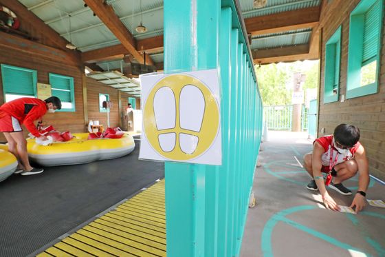 Caribbean Bay employees place stickers on the ground to ensure those lining up for rides maintain social distancing measures. The water park used to have a daily limit of 20,000 visitors but has drastically dropped that threshold to just 1,200. [NEWS1]