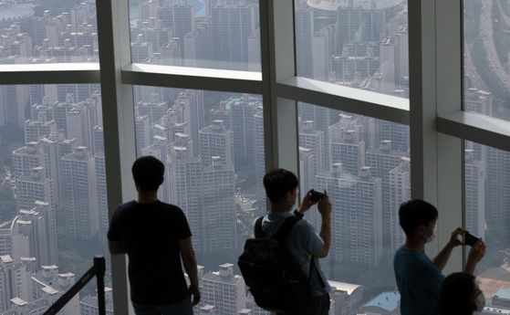 Visitors to Lotte World Tower in Songpa District, southern Seoul, look out at the view of apartment buildings. Songpa District is subject to tighter regulations that are likely to pass during the 21st National Assembly. [YONHAP] 