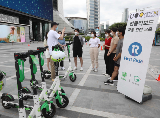 Employees from scooter-sharing service Lime teach people how to correctly park electric scooters at Coex in Gangnam District, southern Seoul, Sunday. [LIME KOREA]