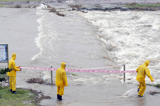 Local government officials set cordon off an area in Gwangju, on Monday, as a stream floods after heavy rainfall. About 200 millimeters of rain pounded South Korea's southern regions on Monday, leaving several people dead and causing traffic accidents, flooding and the destruction of roads, houses and facilities. [NEWS1]