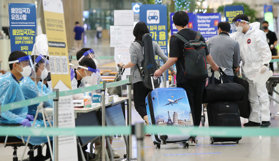 Health officials instruct international arrivals on their transportation options at Incheon International Airport, South Korea's main gateway west of Seoul, on Sunday. The country began on July 13 to require arrivals from high-risk nations to hand in a certificate showing they tested negative for Covid-19. [YONHAP]