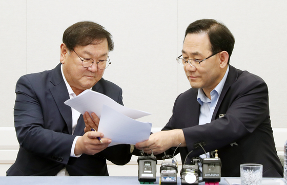 Democratic Party (DP) Rep. Kim Tae-nyeon, left, and United Future Party (UFP) Rep. Joo Ho-young exchange signed agreements on Tuesday.  [YONHAP] 