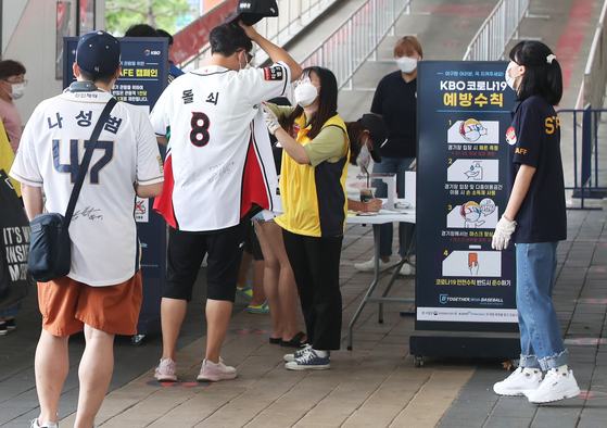 Fans get their temperatures checked as they line up to watch a baseball game at Suwon KT Wiz Park in Gyeonggi Sunday, the first time since the coronavirus pandemic. The Korean government last week announced that spectators will once again be able to watch Korean professional baseball games in stadiums starting Sunday, with seats limited to 10 percent of capacity. [YONHAP]