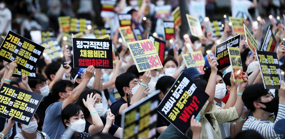 Employees of Incheon International Airport Corporation and young job seekers stage a vigil, holding flashing lights instead of candles, in front of the Korea Deposit Insurance Corporation in Jung District, central Seoul, on Saturday evening, to protest what they called an unfair, opaque decision to upgrade some irregular workers to regular status. [NEWS1]