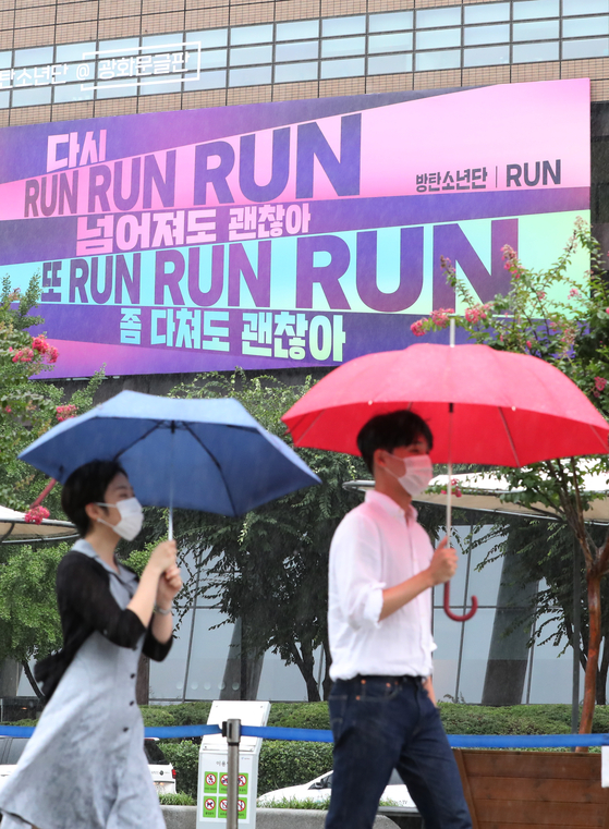 Pedestrians walk past a billboard covered in lyrics from K-pop boy band BTS on Monday, in Gwanghwamun, central Seoul. Kyobo Life Insurance which owns and manages the billboard said it decorated it with lyrics from BTS's song "Run" (2015) to cheer up people exhausted from the prolonged pandemic. [NEWS1]