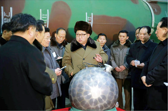 North Korean leader Kim Jong-un, center, poses with what the North claimed was a miniaturized nuclear warhead, in a photograph released by state media in 2016. [RODONG SINMUN]