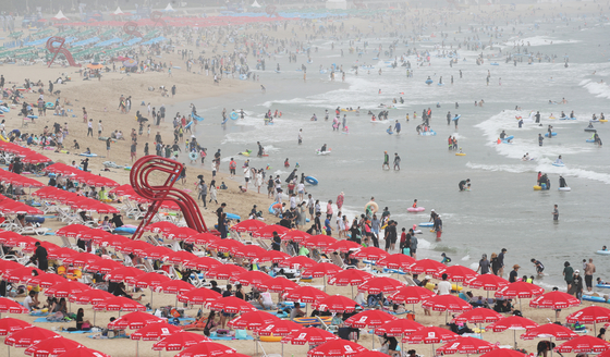 Vacationers cool themselves off at Haeundae Beach in Busan on Tuesday, as a heat wave advisory was issued for the region. [NEWS1]