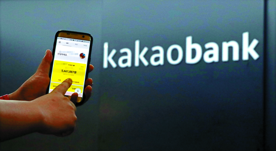 A person uses the Kakao Bank application in front of the bank's office. [YONHAP]