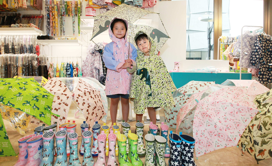 Children model rainwear such as umbrellas and raincoats in Lotte World Mall in Songpa District, southern Seoul, on Thursday. Rainwear brand HAS is offering up to 50 percent off its products for children. [YONHAP]