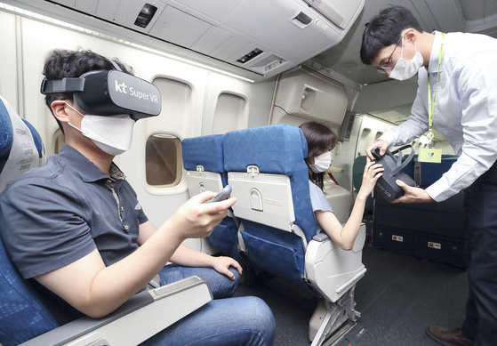 Customers experience immersive media on a Jin Air plane using Super VR, KT's VR platform. KT signed on Thursday a memorandum of understanding with Jin Air and Hanjin Information Systems & Telecommunication to launch in-flight VR services later this year. [YONHAP]