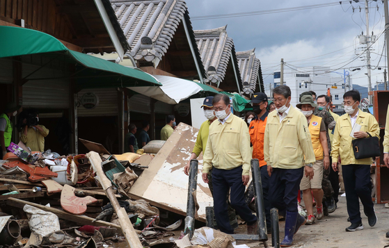 President Moon Jae-in visits a flood-stricken market in Gurye County, South Jeolla, on Wednesday to boost the merchants' spirits. [JOINT PRESS CORPS]