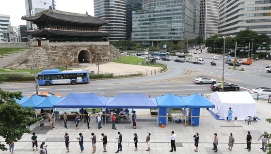 People line up at a Covid-19 testing site in Namdaemun Market, central Seoul, on Tuesday, after health authorities reported nine infections from merchants there. [NEWS1]