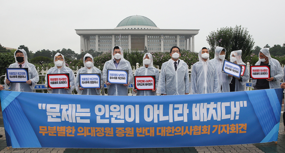Doctors member to Korean Medical Association, the largest union of doctors in Korea, protest in front of the National Assembly in western Seoul on July 23. Their banner reads, "The problem is not in the numbers, it's in the distribution [of doctors]." [YONHAP]