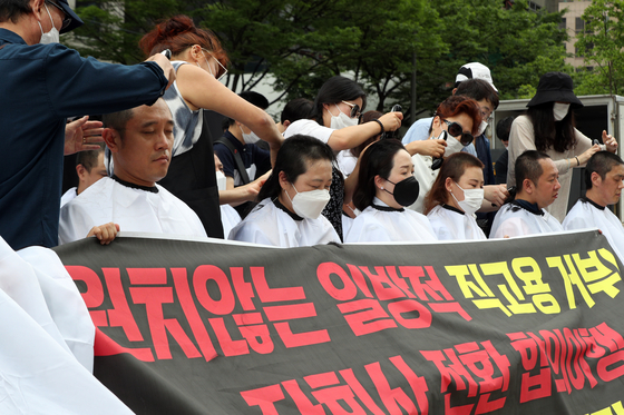 Subcontracted workers from Incheon International Airport shave their heads at an event held in central Seoul on Thursday to show their disapproval of the airport’s announcement that they must pass a test or go through the public recruiting system to be upgraded. [NEWS1]