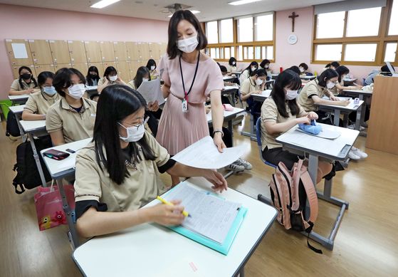 Kim Yu-na, an English teacher at Bakmun Girls’ High School in Songdo, Incheon, hands out learning materials during a class on June 25. [PARK SANG-MOON]