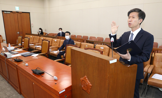 Kim Dae-ji, nominee for the National Tax Service head, undergoes a sworn ceremony before his confirmation hearing on Wednesday. Seats for lawmakers' aides and journalists are nearly empty to maintain the elevated preventive measures.  [YONHAP] 