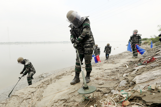 At an estuary of Imjin River in Gimpo, Gyeonggi, on Thursday, marines in protective gear search for land mines that may have washed downstream from North Korea by recent torrential rainfall and flooding.  [YONHAP]