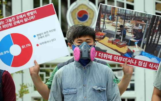 Workers participate in a press conference organized by the Korean Federation of Construction Industry Trade Unions (KFCITU) in front of the Central Government Complex in central Seoul, on Thursday. During the conference, the KFCITU requested that the government come up with some measures that can provide better working environments on construction sites, such as the shortening of working hours as a heat wave hits much of the country. [YONHAP]