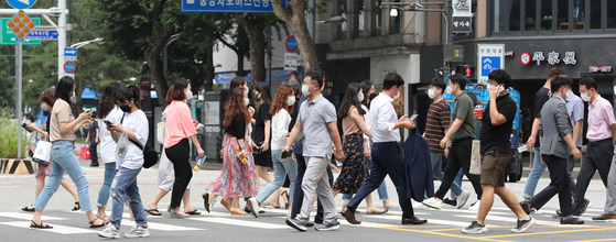 Pedestrians cross a road in central Seoul while wearing face masks Monday, the first day that the Seoul Metropolitan Government's face mask order went into effect. [NEWS1] 