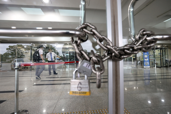 A gate at the National Assembly's main building is locked after the legislature shut its key buildings after a photojournalist covering the Democratic Party was confirmed infected with Covid-19.  [YONHAP] 