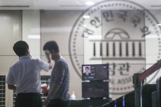 Officials from the National Assembly building management office check a visitor’s temperature at the entrance to the main building of the National Assembly in Yeouido, western Seoul, on Sunday. The National Assembly reopened on Sunday after being shut down for three days for disinfection after a photojournalist who covered the ruling party's leadership meeting on Wednesday tested positive. The National Assembly will open the regular session on Sept. 1. [NEWS1]