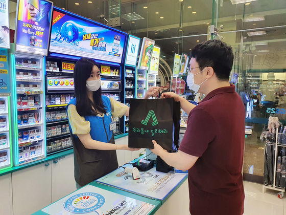A person who signed up to provide on-foot delivery service to people nearby a GS25 convenience store receives a package. [GS RETAIL]